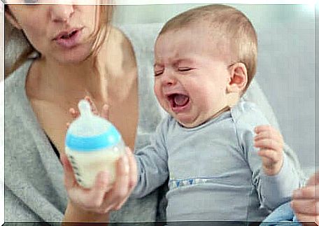A baby crying in front of his bottle.